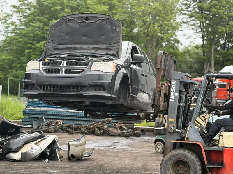 Forklift moving a Dodge Grand Caravan in the Recyclage Auto St-Jean yard