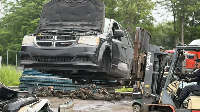 Forklift moving a Dodge Grand Caravan in the Recyclage Auto St-Jean yard