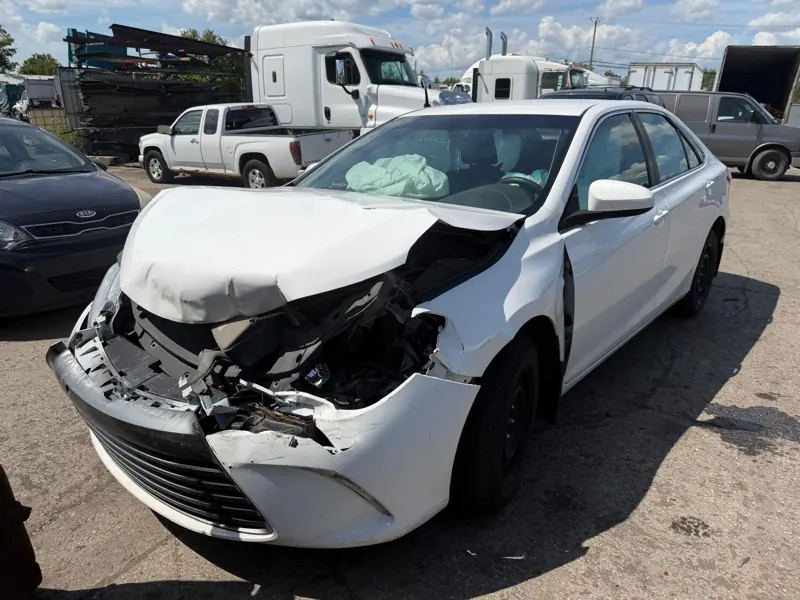 Berline blanche accidentée, avant enfoncé et coussin gonflable déployé, dans la cour de Recyclage Auto St-Jean