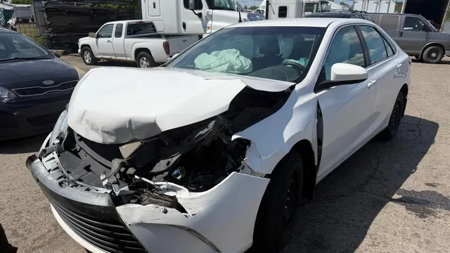 Berline blanche accidentée, avant enfoncé et coussin gonflable déployé, dans la cour de Recyclage Auto St-Jean